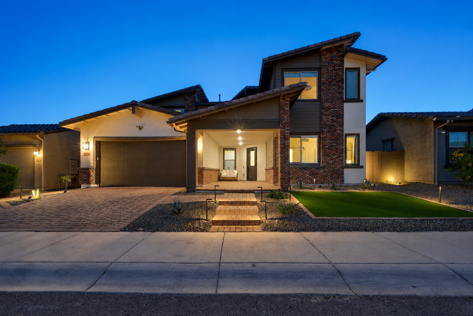 Front exterior of a modern Arizona home photographed at blue hour with warm interior lighting