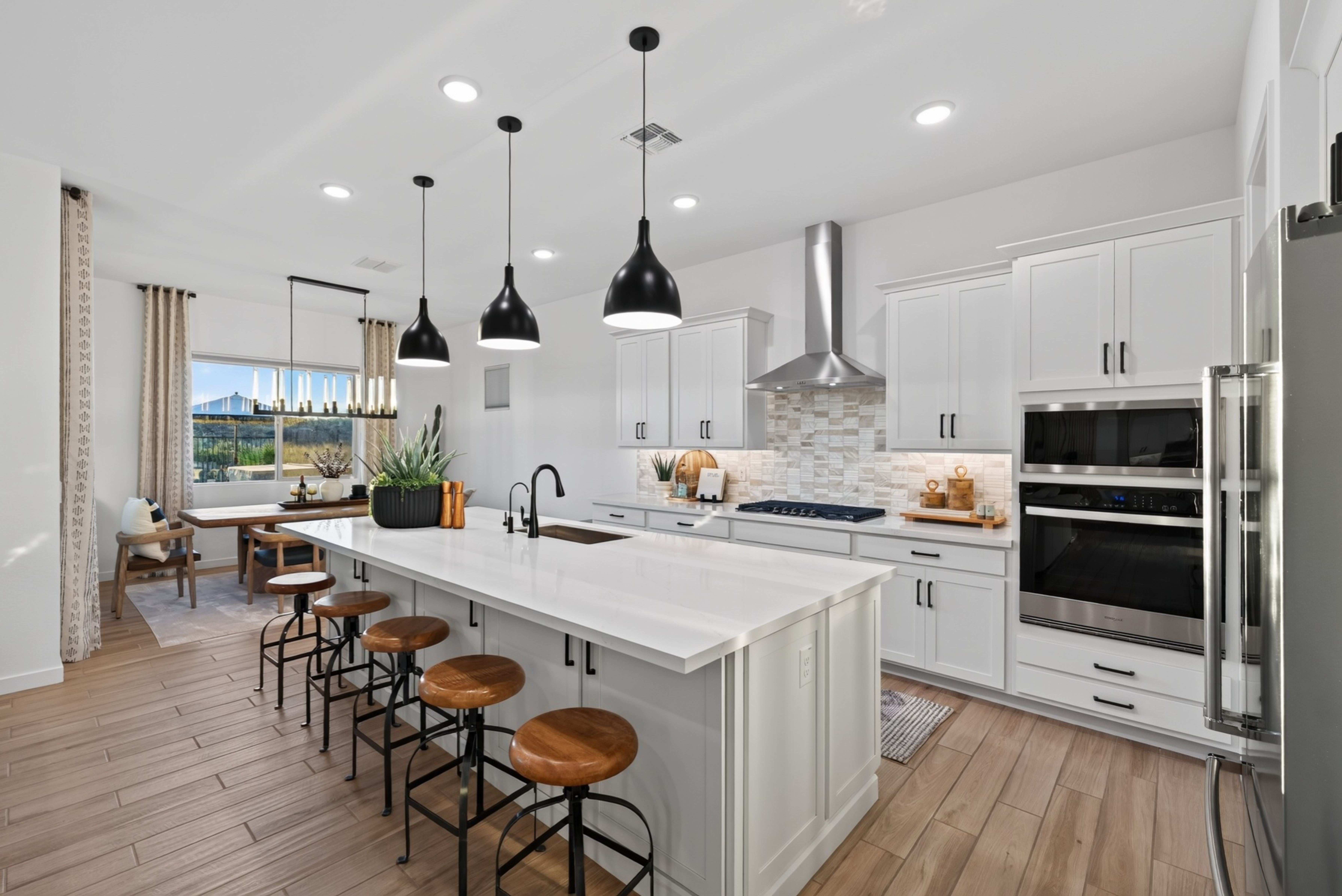 Modern residential kitchen with a large island, pendant lighting and a dining nook opening to a mountain view